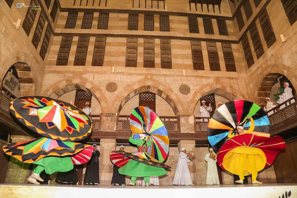 Egyptian tanoura dancers perform in colorful skirts inside a historic Cairo cultural venue.